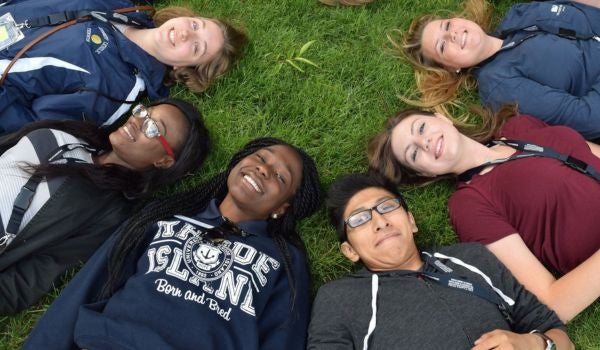 students laying in the grass smiling