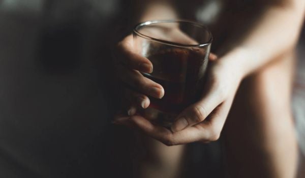 a person holds a glass of alcohol