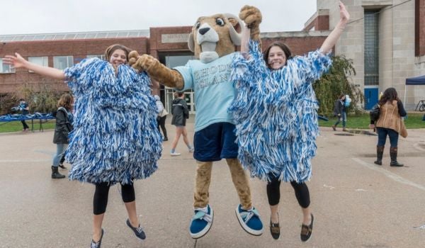 two sstudents dressed as pom poms jumping for joy with rhody the ram