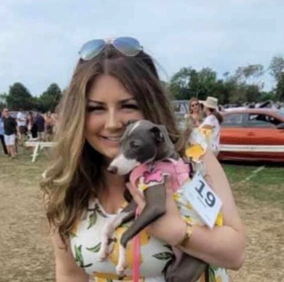 Kathryn Zimmerman smiles at the camera holding her cute doggo.