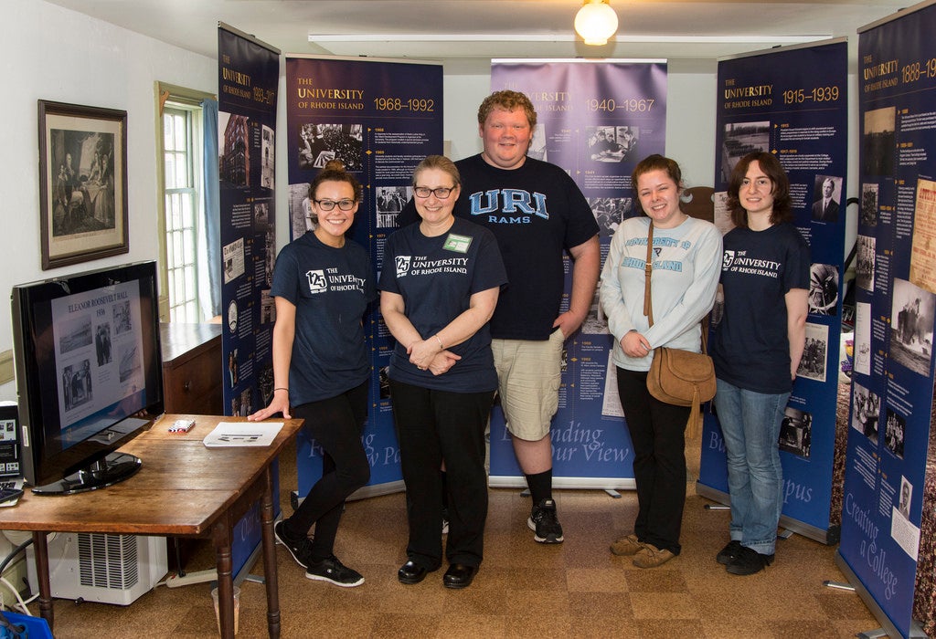 Five people posing for a picture wearing University of Rhode Island Shirts