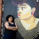 Artist Angela Gonzalez, "agonza" in front of her mural