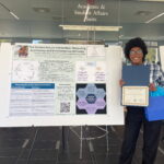 Yvonne Wingard poses next to their poster presentation, holding a certificate of participation awarded to students who presented their research at the International Graduate Student Showcase. Wingard's poster is titled, "The Human-Nature Connection: Measuring Ecoliteracy and Environmental Attitudes."