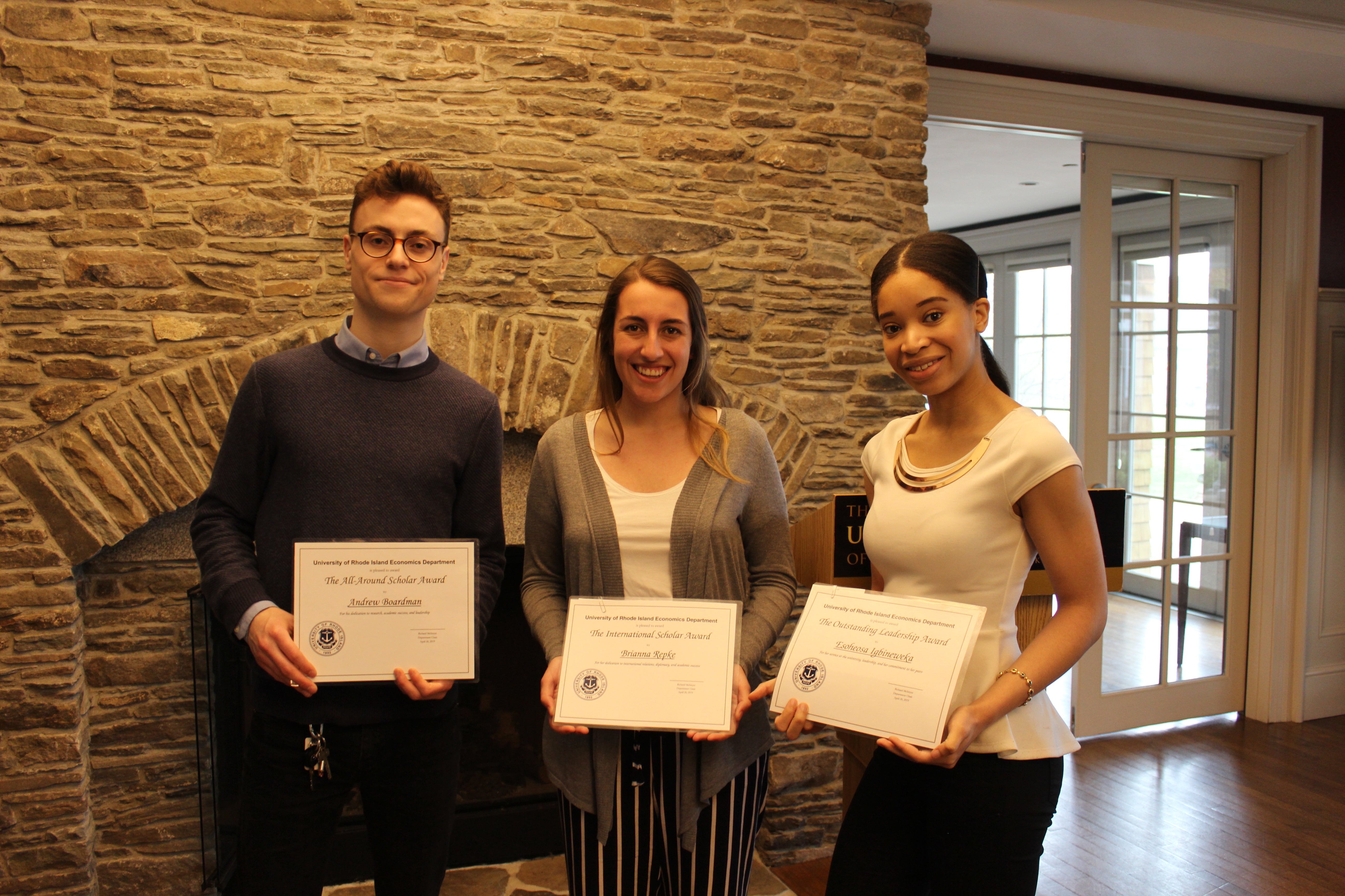 three students holding up award certificates