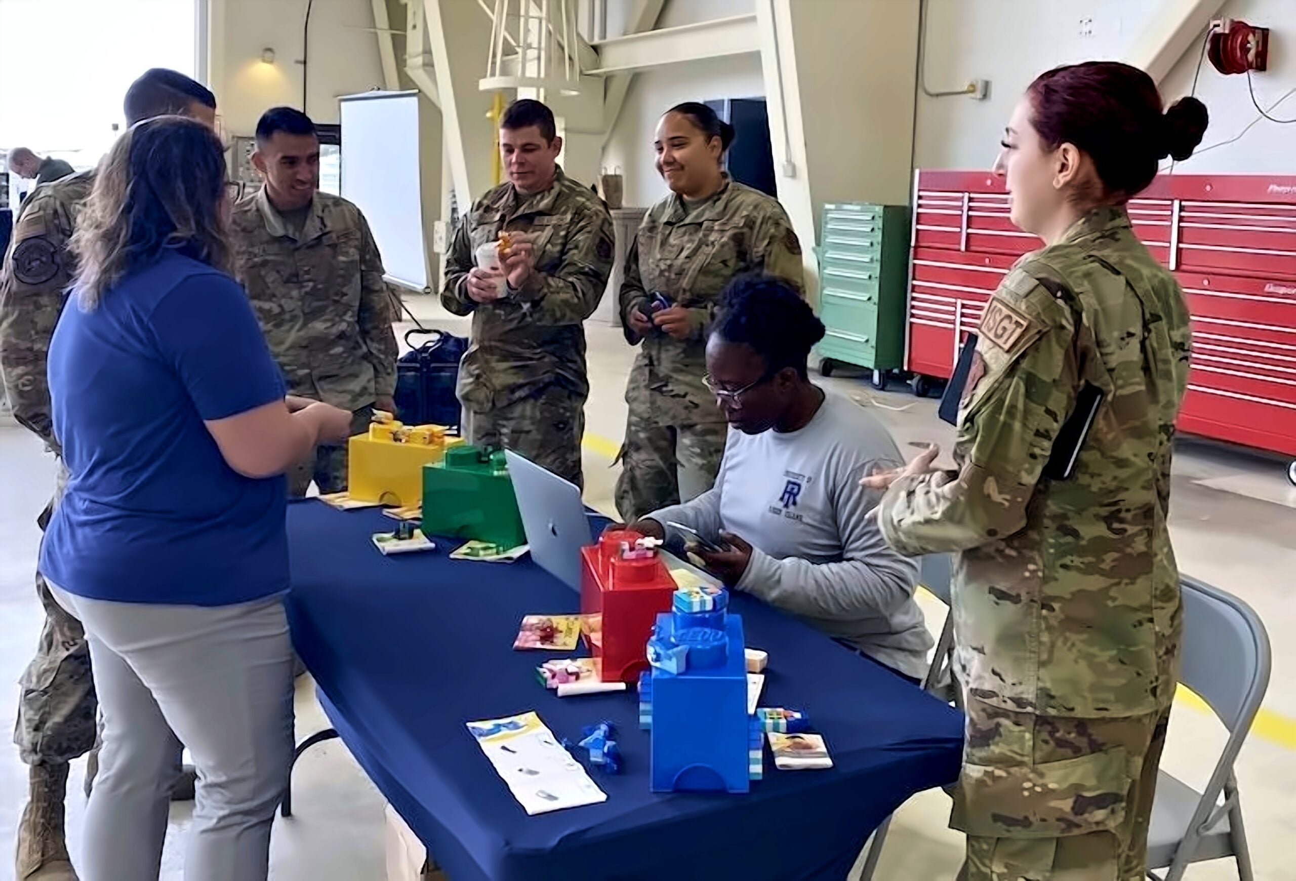 EDI team members lead an activity with uniformed Rhode Island National Guard members around a table of colorful LEGO bins