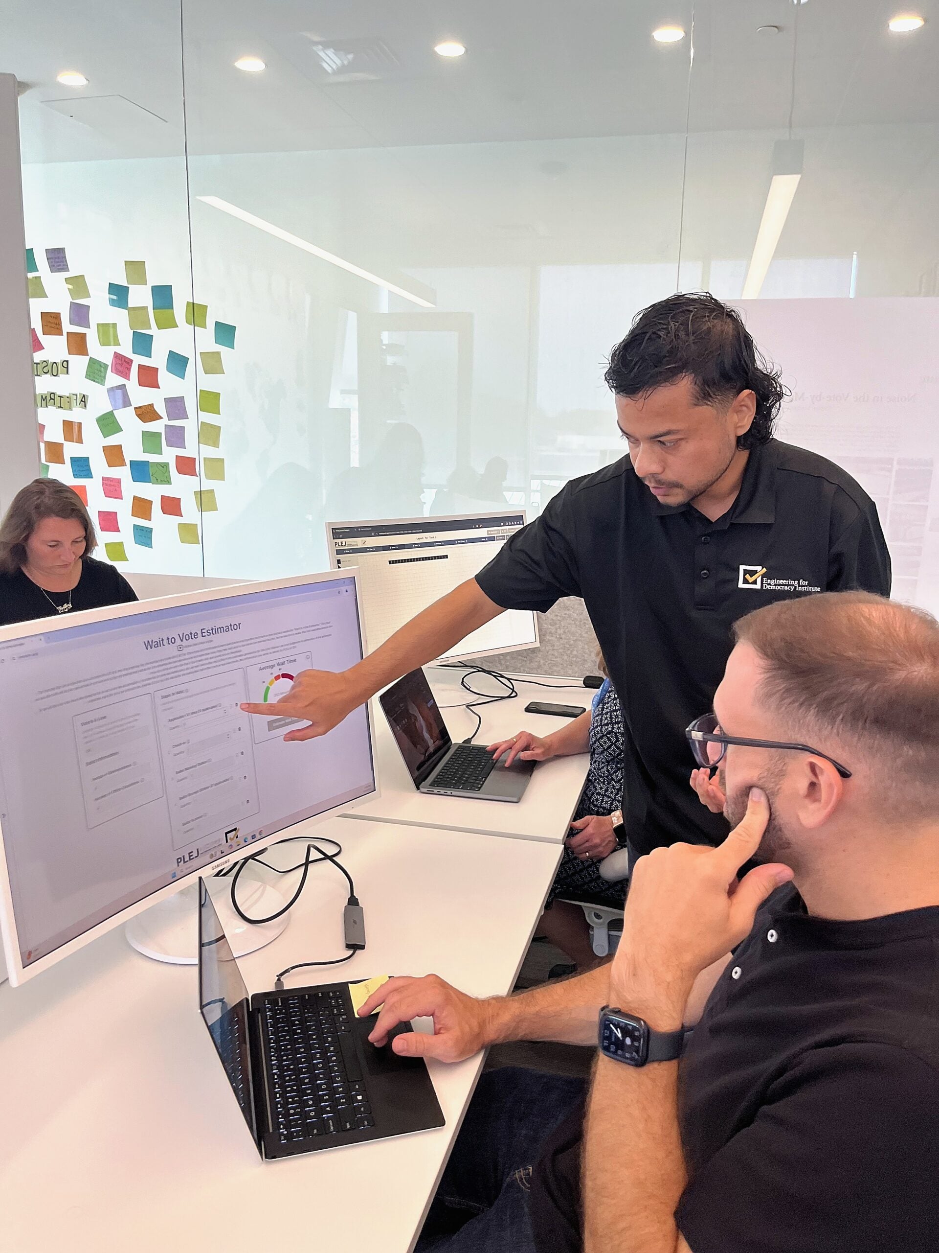 Two workers reviewing data on a computer monitor, one pointing at the screen