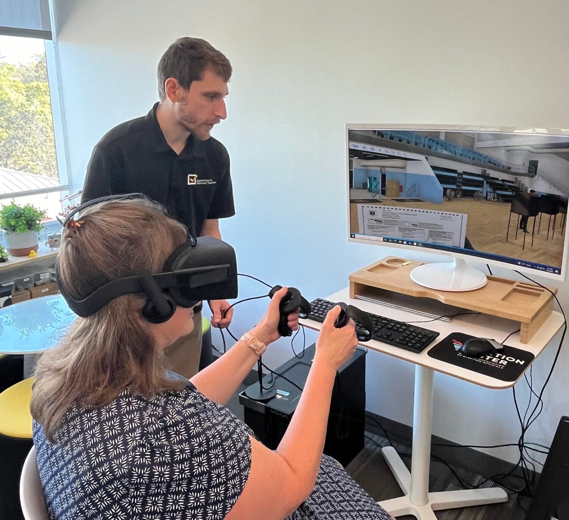Person in chair using VR headset with a screen in front of them with a person looking on