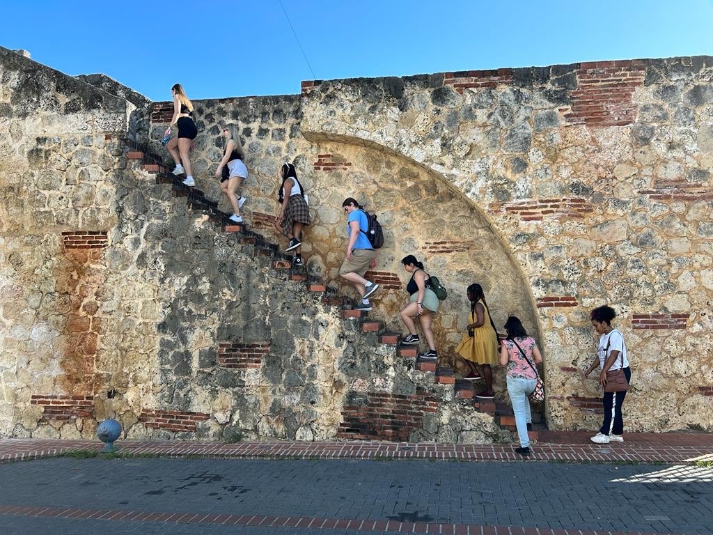 Decolonial tour in the Zona Colonial neighborhood of Santo Domingo. Students walking up and along the La Puerta de las Reales Atarazanas built in the 16th century under the rule of Diego Colón (son of Christopher Columbus/Cristobal Colón) as part of an entrance for slaves brought to the island.
