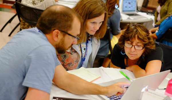a teacher works with two students at a table