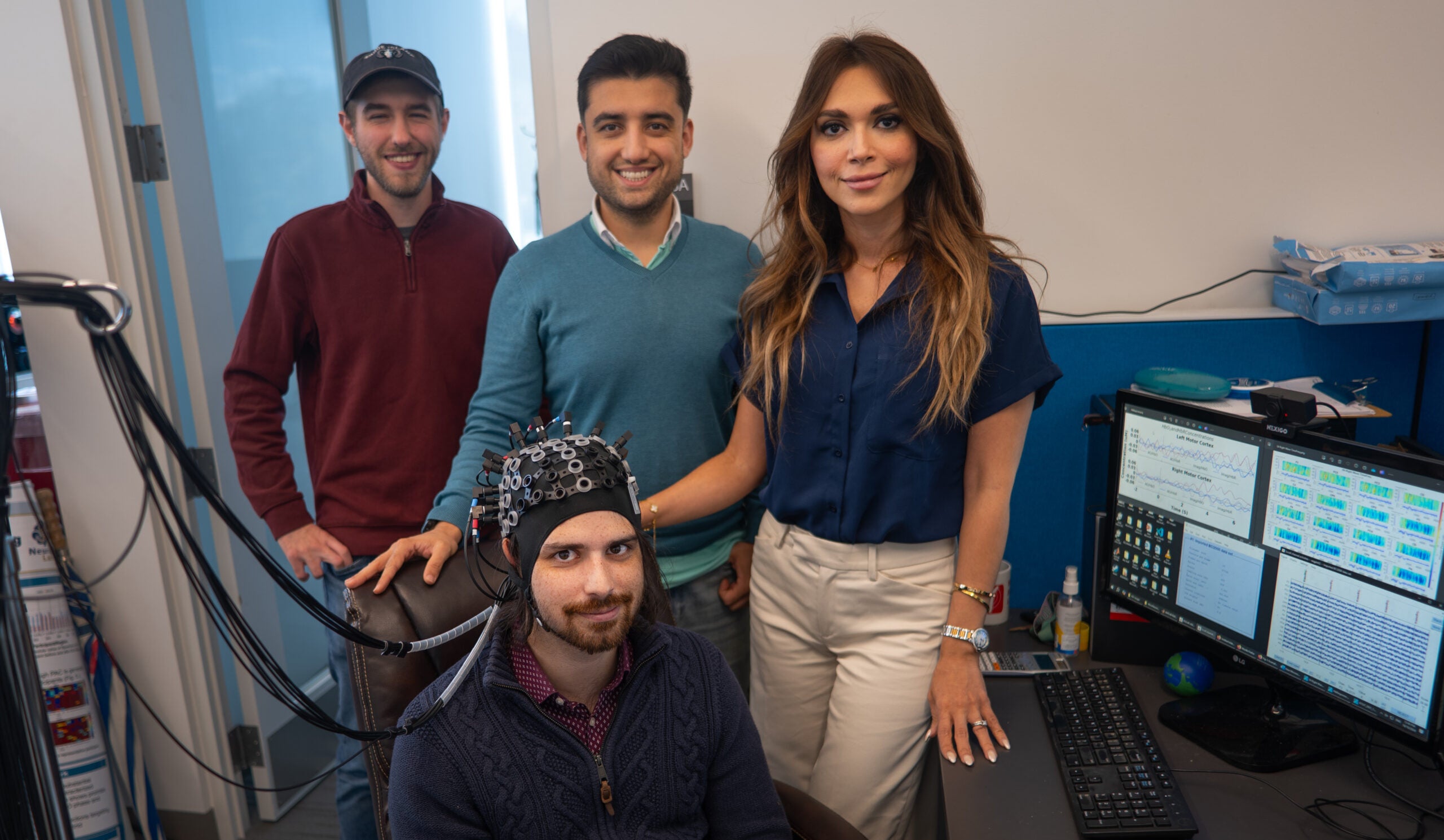 Ph.D. students John McLinden and Behtom Adeli stand with associate professor Yalda Shahriari and master’s degree student Alex Cerullo, seated, in the NeuralPC Lab