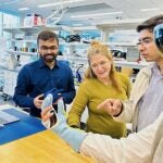 three professors observe student utilizing a smart glove and VR technology