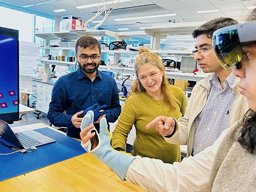 three professors observe student utilizing a smart glove and VR technology