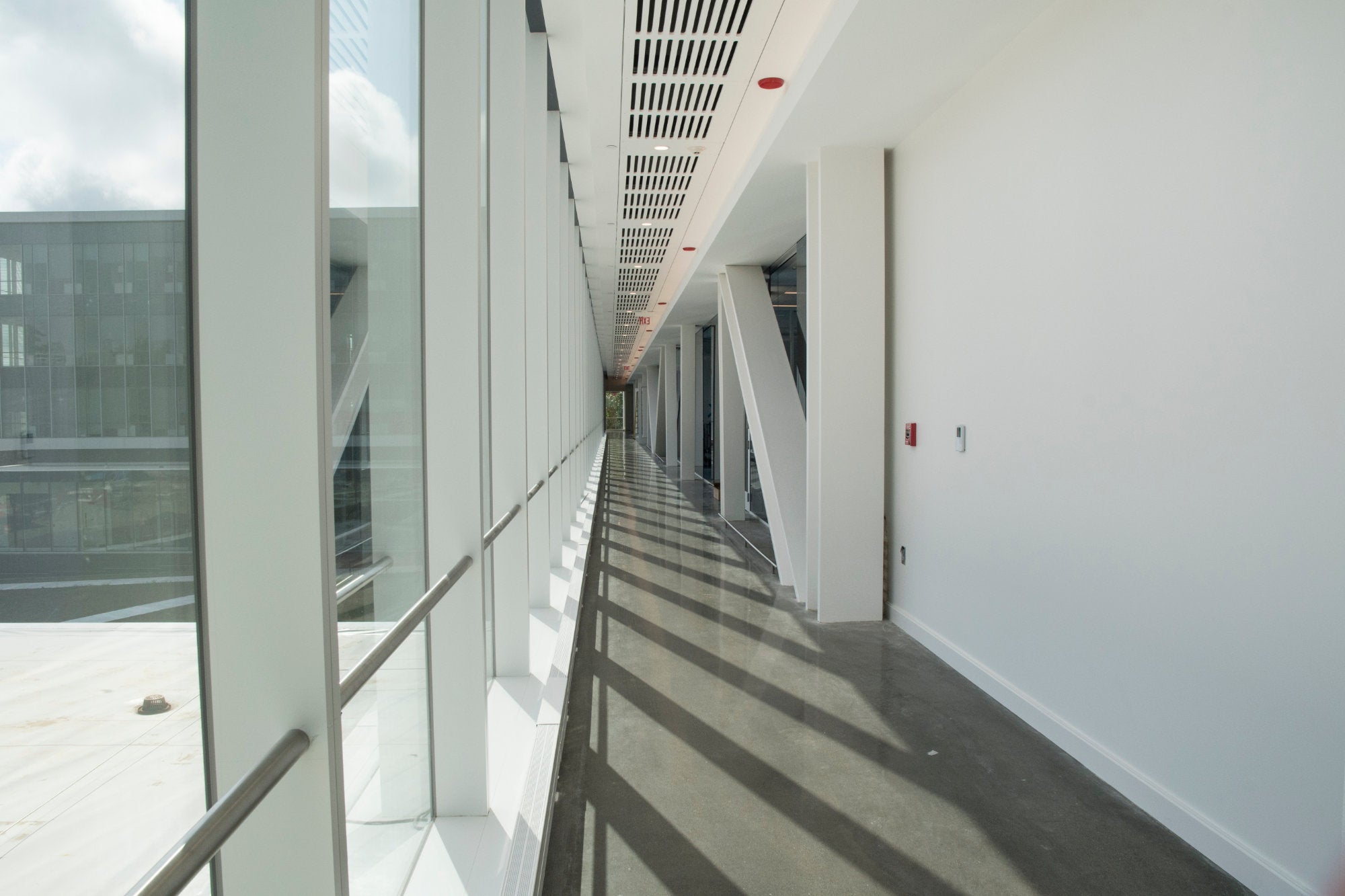 A bright open corridor on the fourth floor shows the building's metal truss support system.