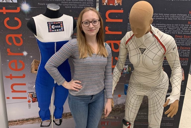Rachel Bellisle stands between a gravity loading countermeasure suit (left) and the BioSuit.