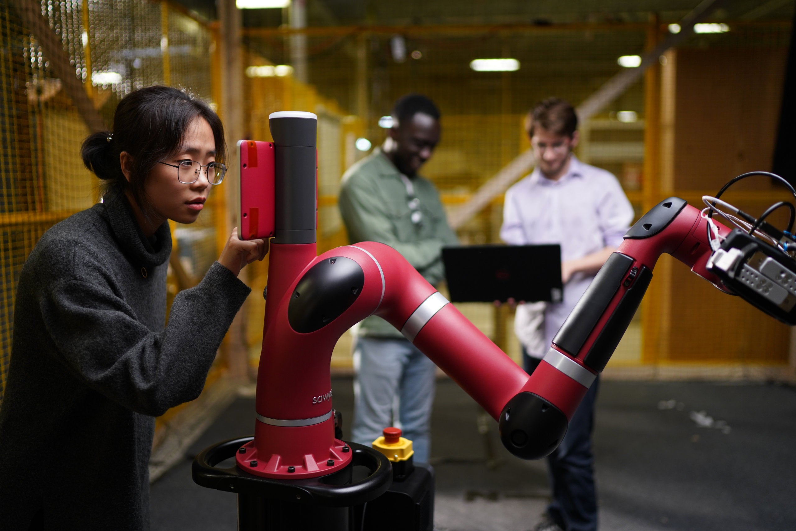 A team of students works with a robotic arm
