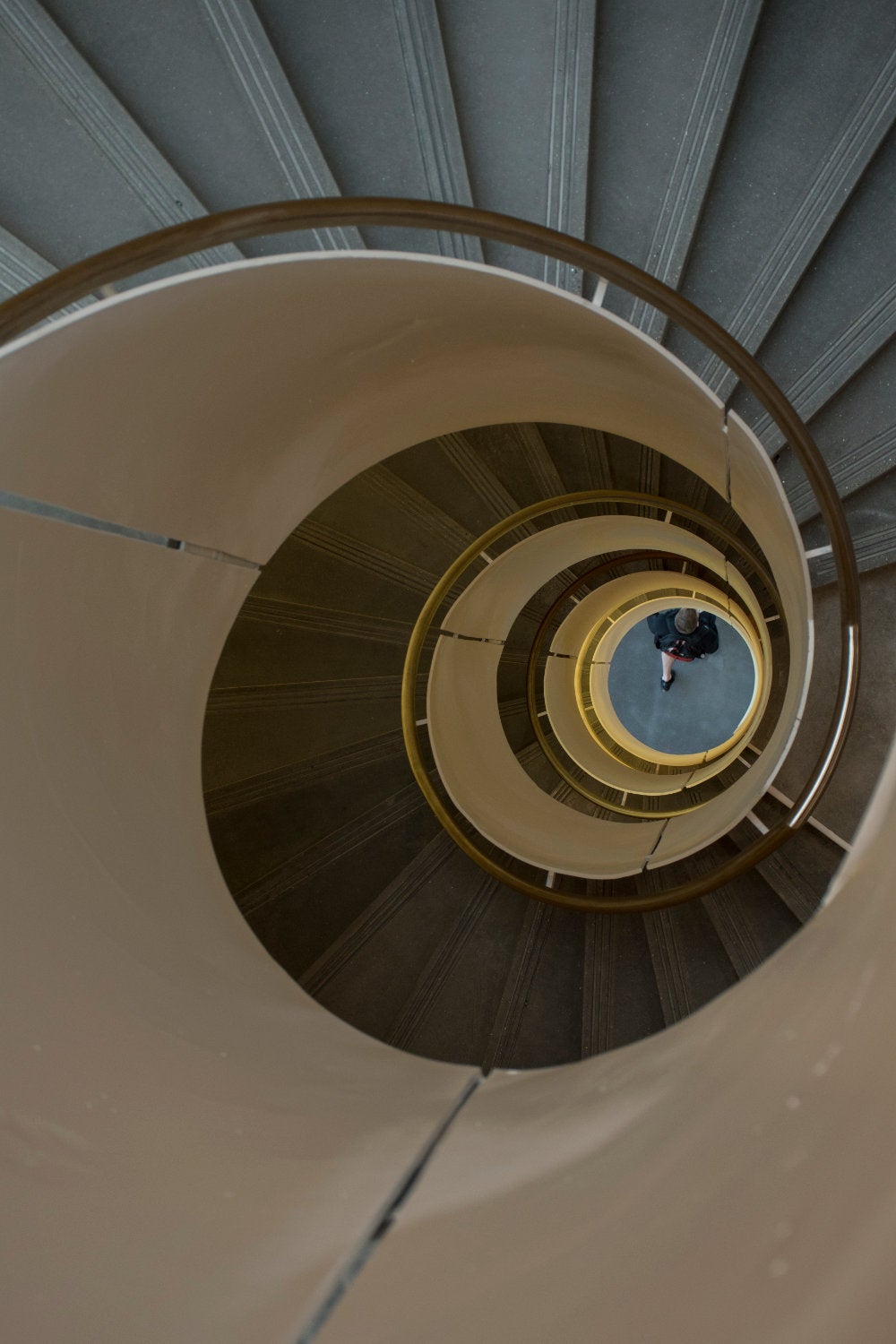 A view of a passerby walking beneath the center of the spiral staircase