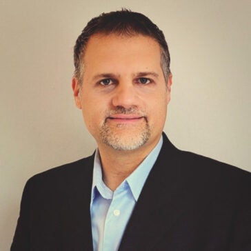 A headshot of Erik Anderson wearing a dark suit in front of a neutral background