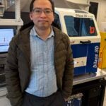Yang Lin in his lab next to a high precision 3D printer