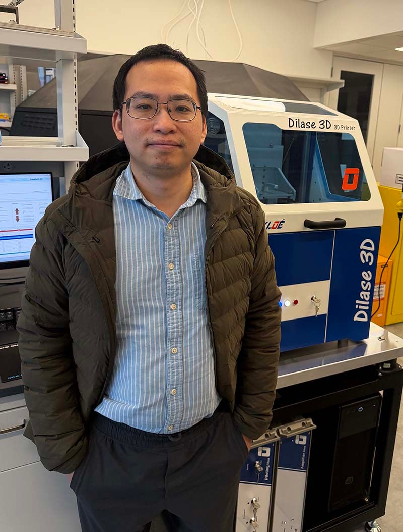 Yang Lin in his lab next to a high precision 3D printer