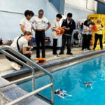 student stand outside a pool to watch robots perform in the water