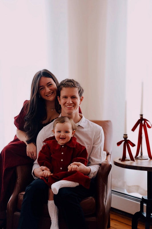 A family of three poses together for a holiday photo