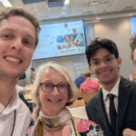 Three students and a staff member pose together at a conference