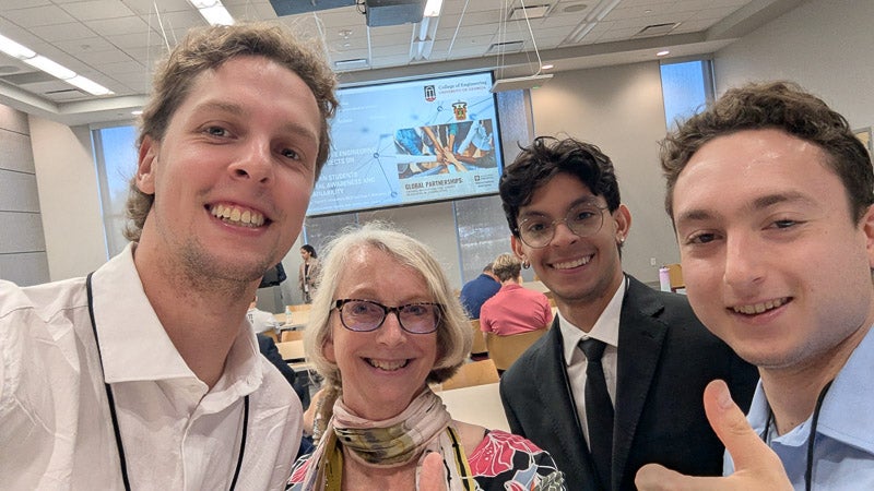 Three students and a staff member pose together at a conference