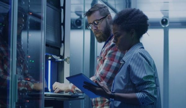 two computer science professionals stand in a server room together