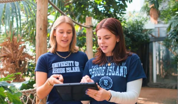 two students inside of a greenhouse habitat