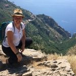 URI Professor and Fulbright recipient Rosaria Pisa poses before a mountain cliff of terraced farms on the Amalfi coast