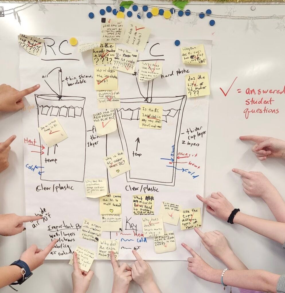 student hands pointing at a learning chart