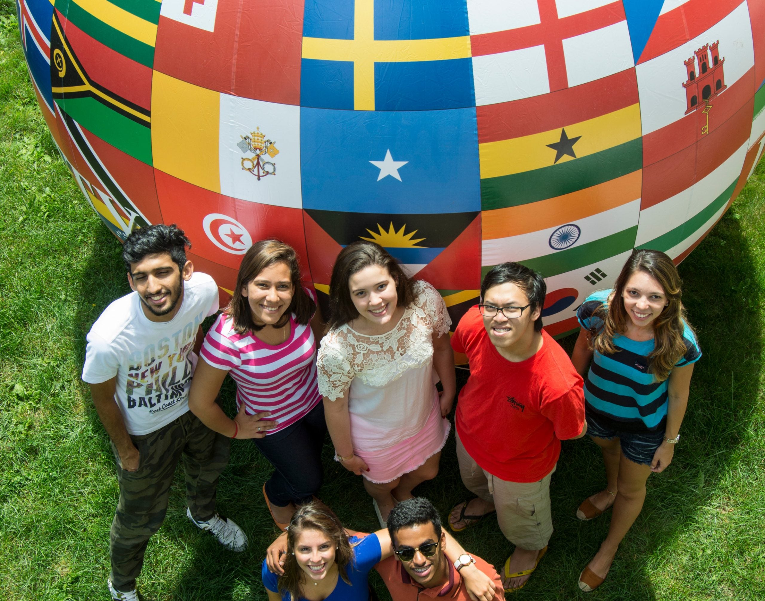 A group of students next to a giant ball decorated with international flags.