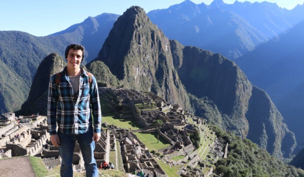 A student standing in the mountainous landscape of Machu Picchu in Peru.