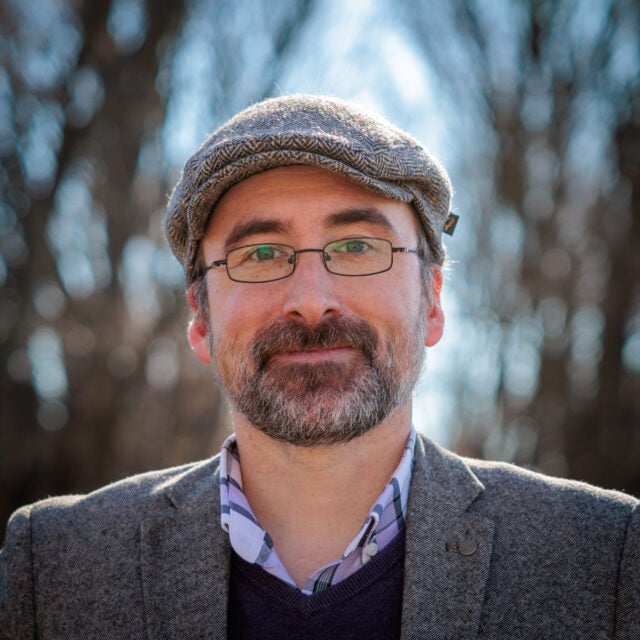 A portrait of Rob Coyne in front of a blurred backdrop of trees.