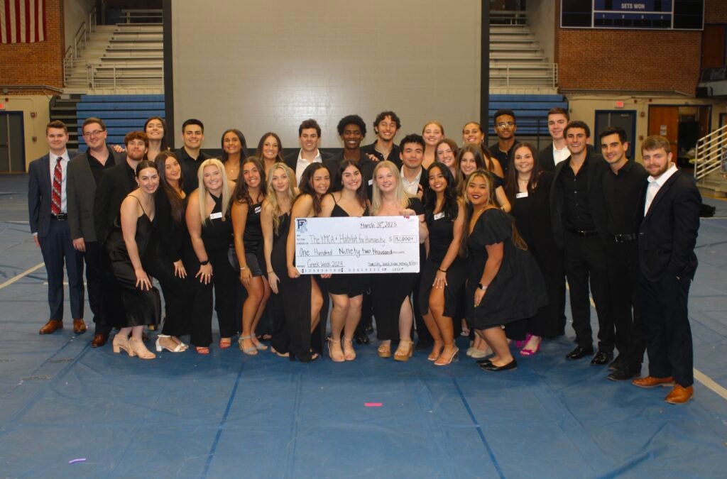 a group of greek students present a check to the YMCA