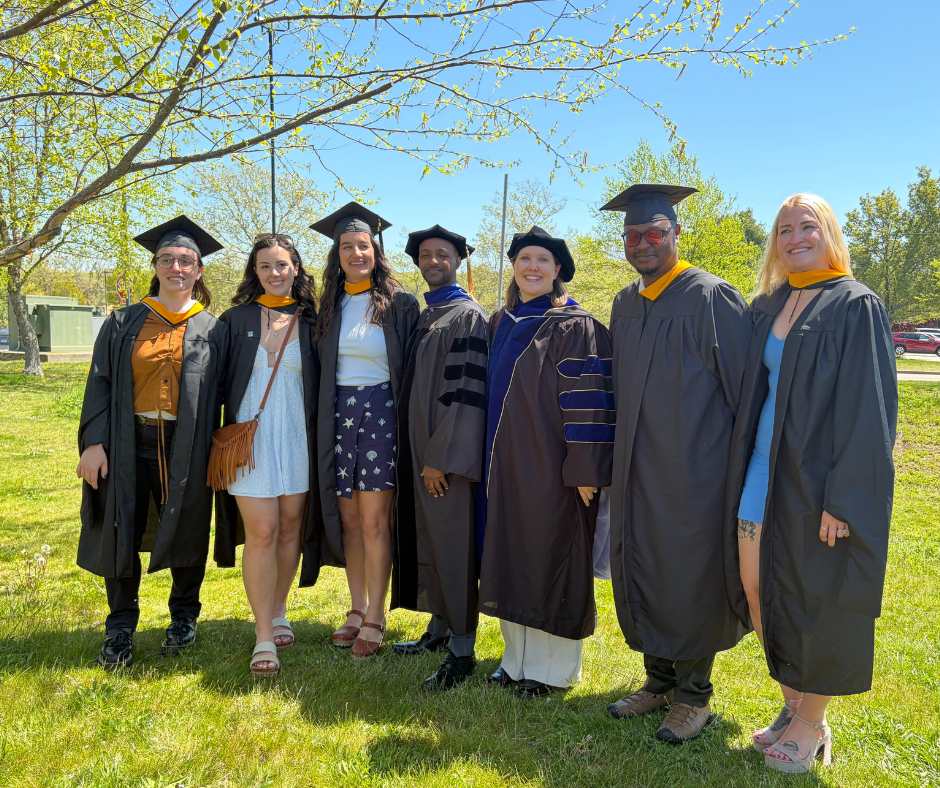 A group of graduates smiles in their gowns. 