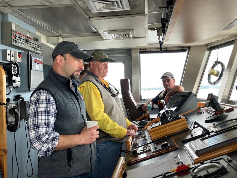 Chris Armanetti on the bridge of the ship with two men to his left.