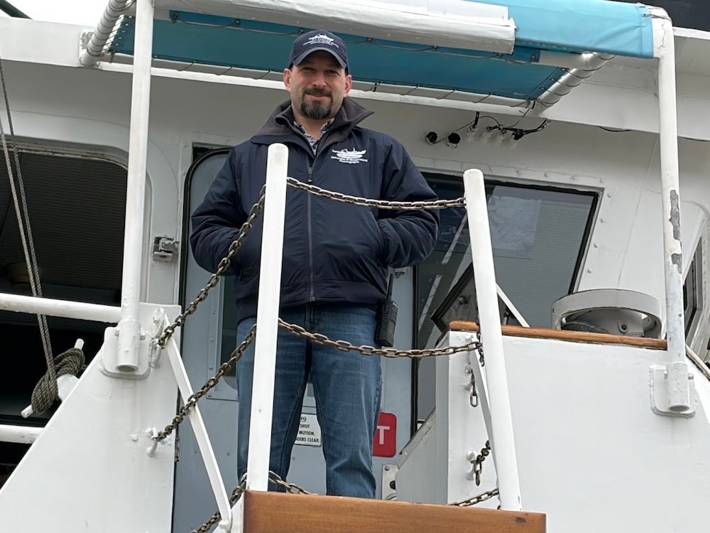 Chris Armanetti aboard the research vessel Endeavor, standing on a platform just outside from the bridge (the command center of the ship).
