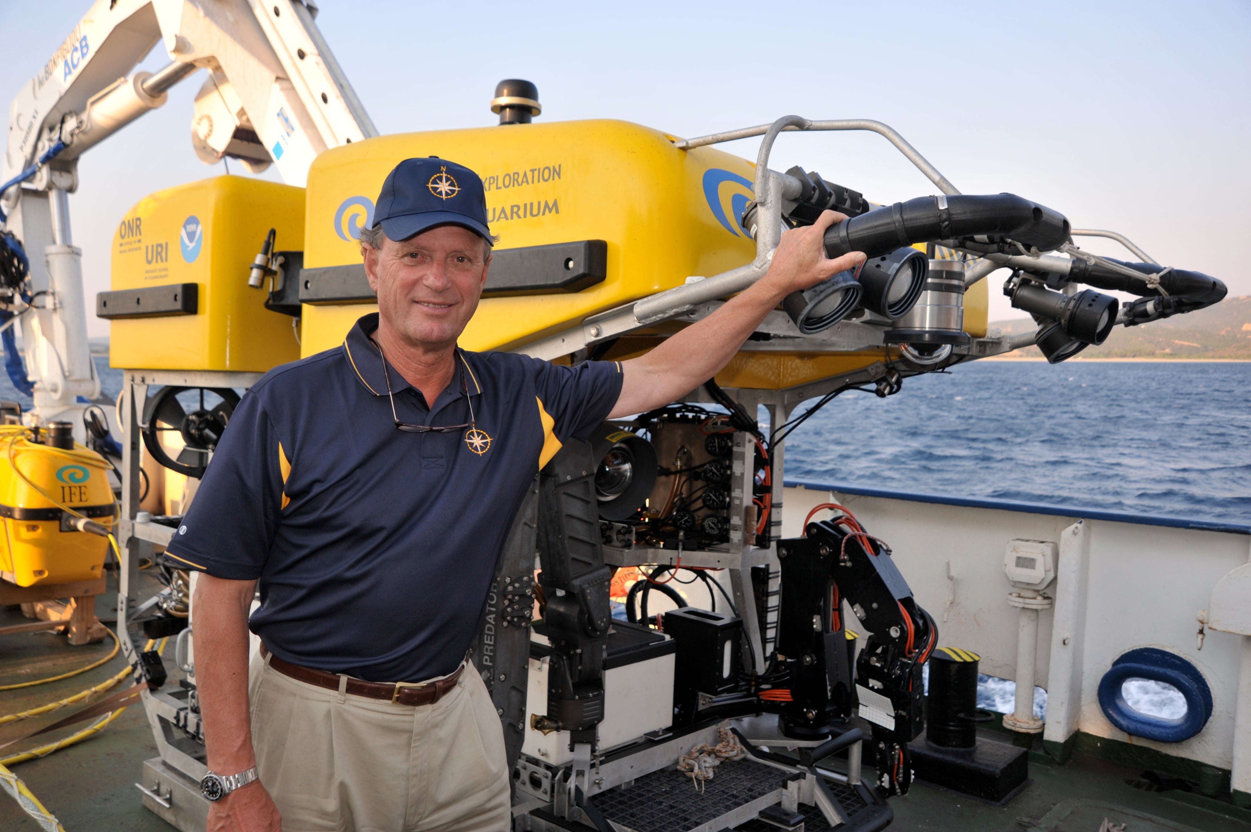 Robert Ballard standing next to a remotely operated vehicle (ROV) aboard E/V Nautilus.