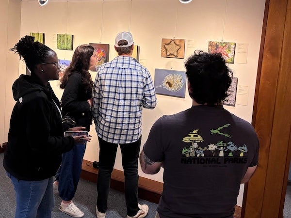 Four people inside the Studio Blue Gallery looking at art on the walls.