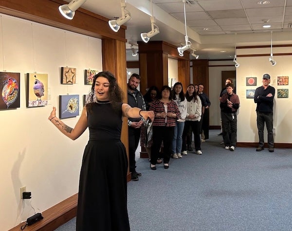 Alyssa Tsukada speaking to a crowd in the Studio Blue Gallery during an opening reception.