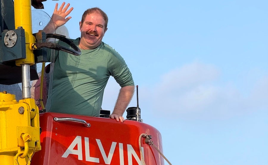 Sam Katz waving and smiling as he climbs down into the submarine Alvin.