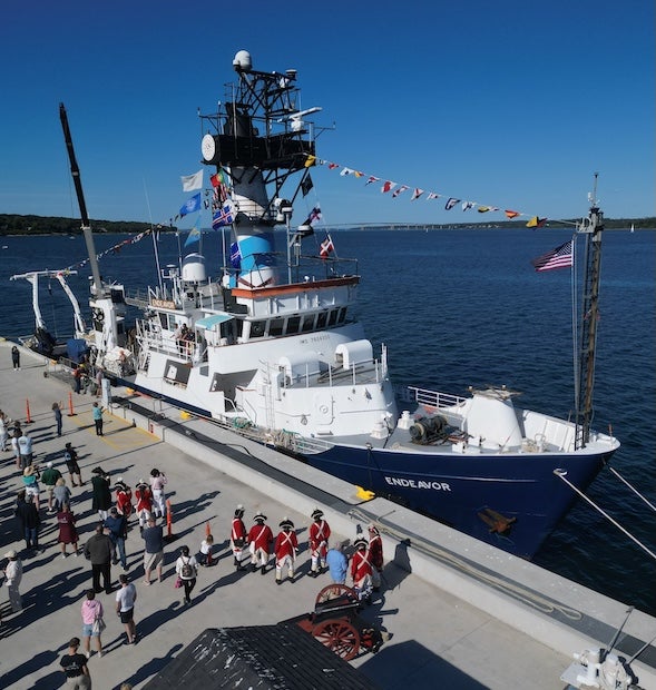 A research vessel at a pier with a large crowd of people. 