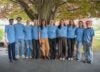 Group of new grads in blue shirts.