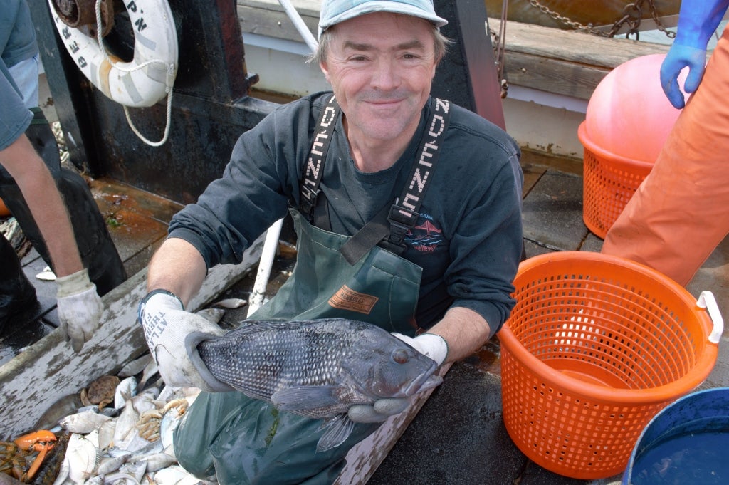 GSO professor Jeremy Collie on a boat and holding a fish.