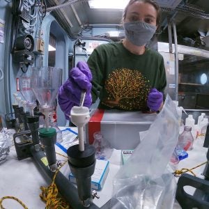 Female student working in a lab aboard R/V Endeavor. She is wearing a face mask.