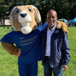 Photo of Greg Peppers on the quad posing with Rhody the Ram