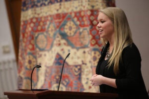 Student speaking publicly at an event to help Afghan women
