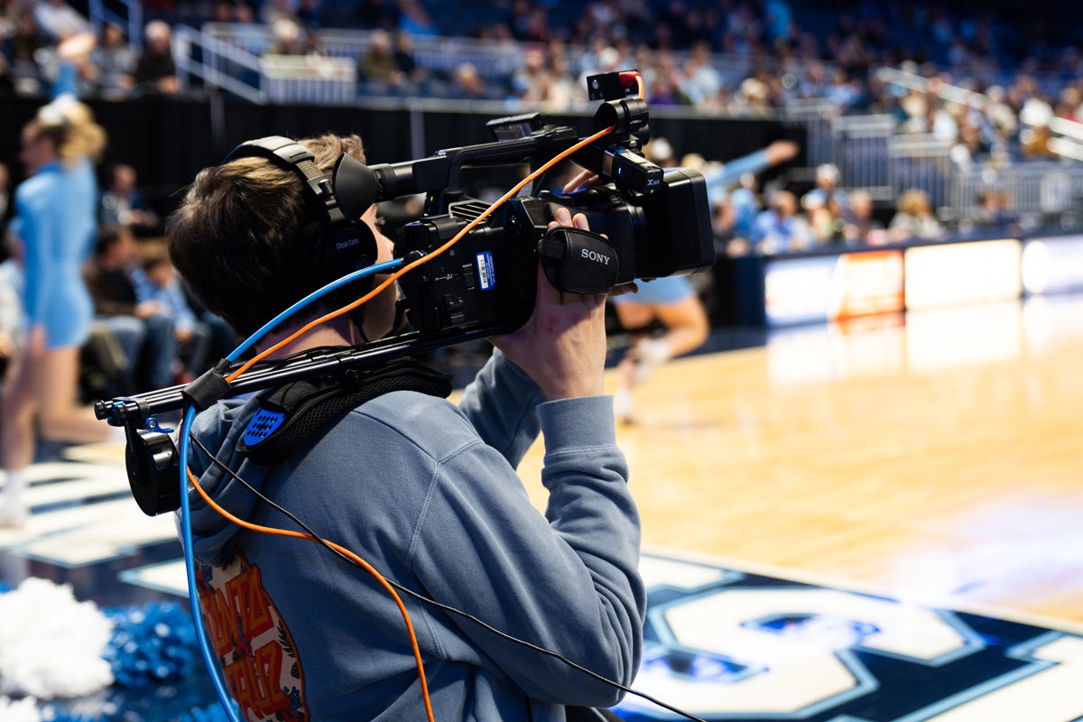 Student with broadcasting camera on the basketball court