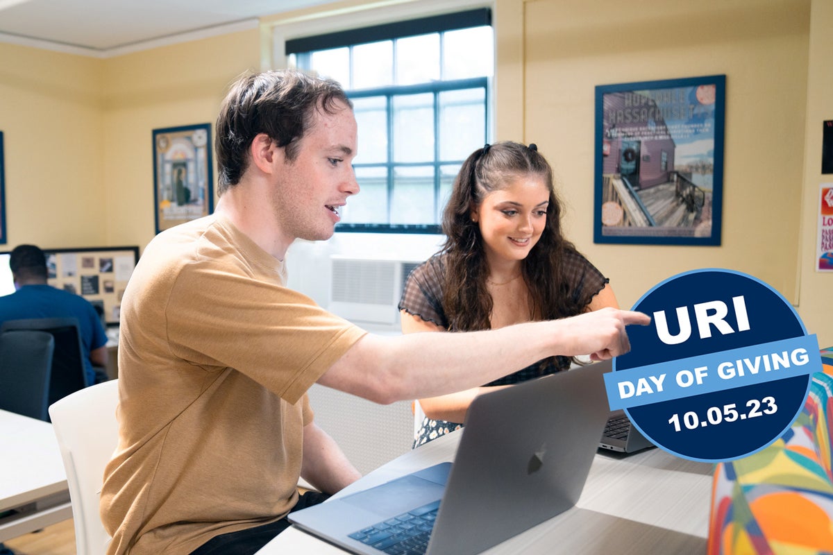 Two students working together in a classroom with the Day of Giving Logo on the image